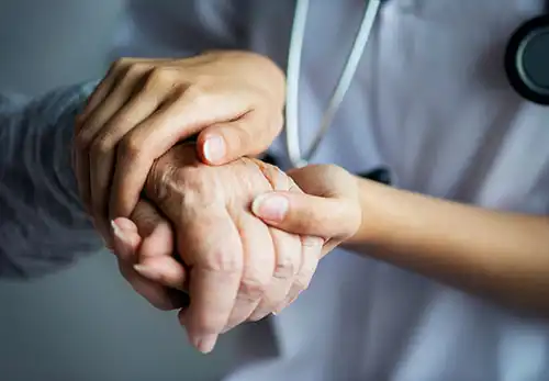 A doctor holding an elderly patient's hand