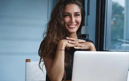 A woman smiling in front of a laptop